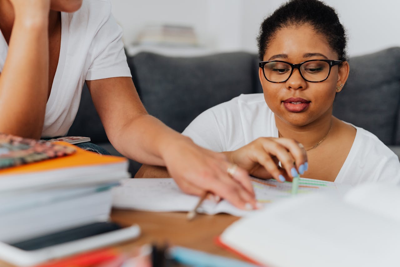 Focused learning session with a tutor and an African American woman, studying together at home.
